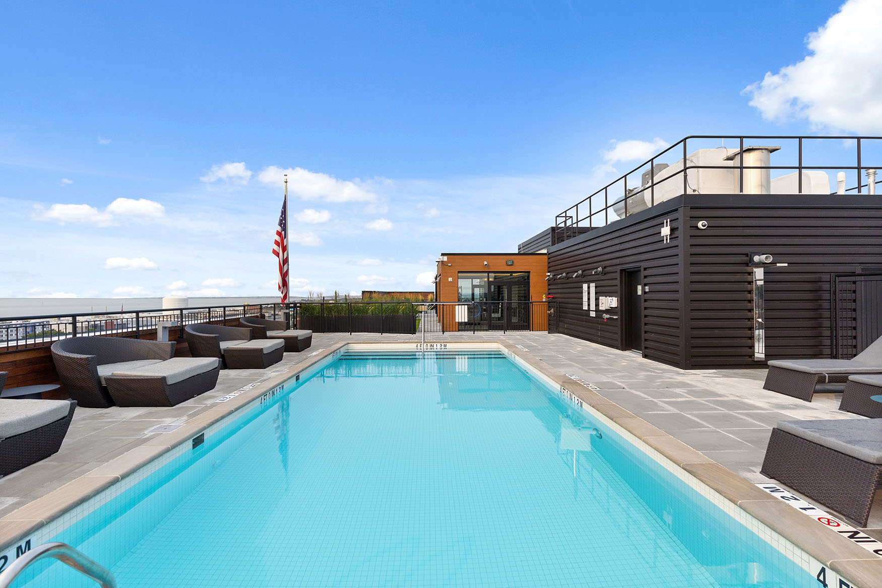 View of rooftop pool with lounge chairs and sky in background